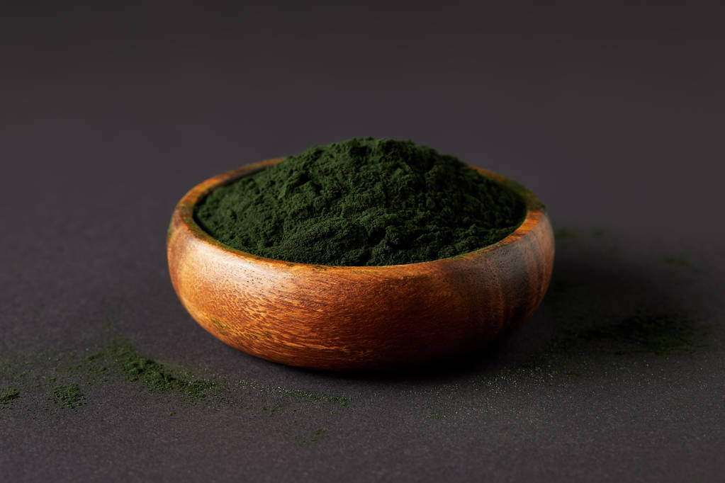 グレーのテーブルの上椀でスピルリナ藻パウダー  - 写真・画像