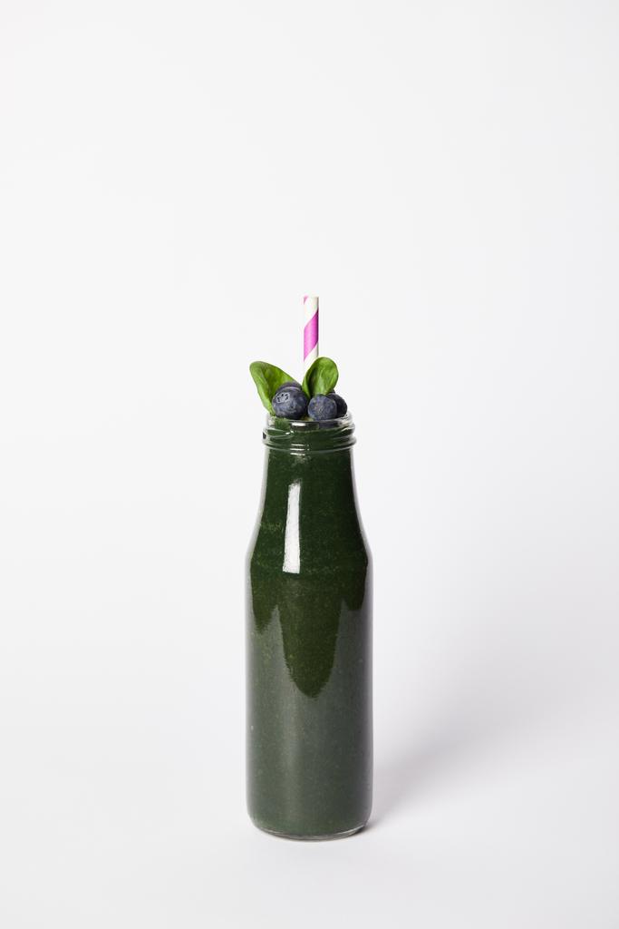 бутылка спирулинового смузи с мятными листьями, черникой и соломой на сером фоне
  - Фото, изображение