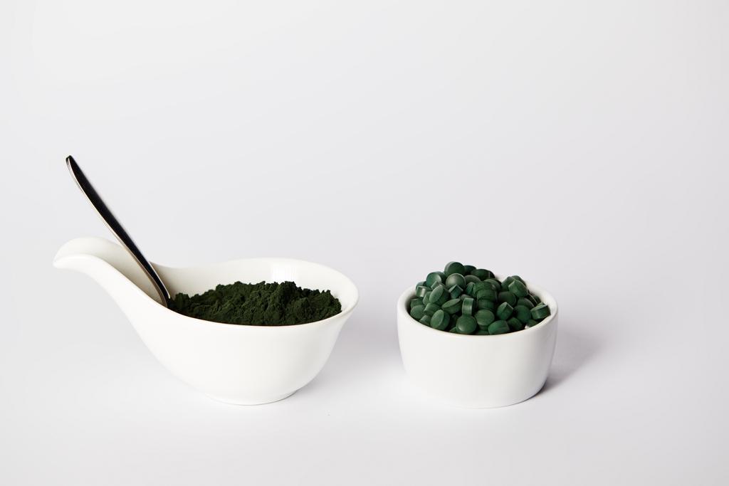 spoon, spirulina powder and spirulina pills in bowls on grey background  - Photo, Image