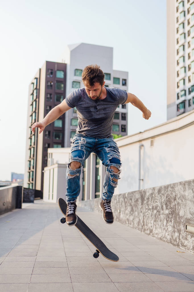 Скейтбордист, выполняющий трюк на скейтборде на улице города - Фото, изображение