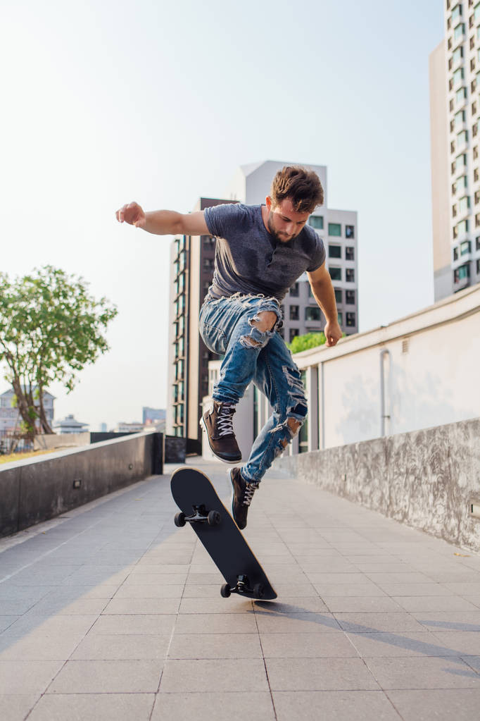 Скейтбордист, выполняющий трюк на скейтборде на улице города - Фото, изображение