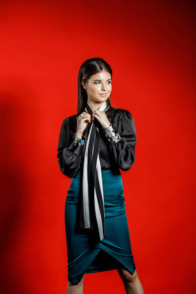 Genç model kırmızı bir arka plan üzerinde rahat kıyafetler içinde stüdyo portre. Siyah gömlek ve mavi etek stüdyoda poz genç kadın  - Fotoğraf, Görsel