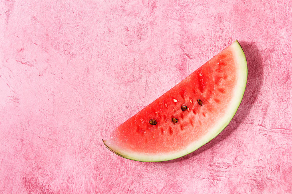 Rijpe segment van watermeloen via roze textuur achtergrond. Platte lay, ruimte. - Foto, afbeelding