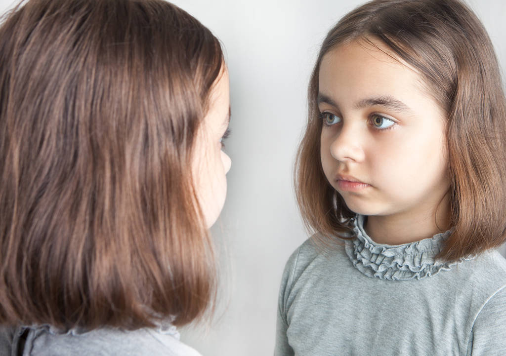 Adolescente menina olha para seu reflexo no espelho
. - Foto, Imagem