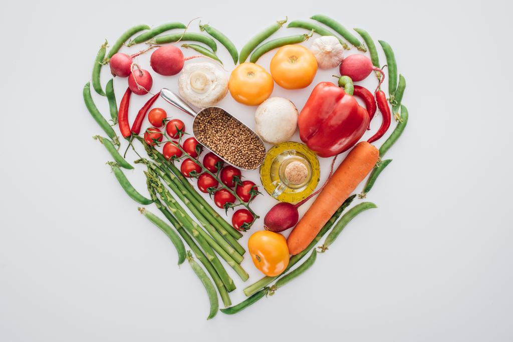 vista superior del corazón hecho de guisantes verdes, espárragos y verduras maduras con especias aisladas en blanco
  - Foto, imagen