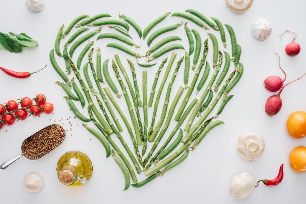 ylhäältä näkymä sydämen valmistettu tuoreista vihreitä herneitä ja kypsiä vihanneksia eristetty valkoinen
 - Valokuva, kuva