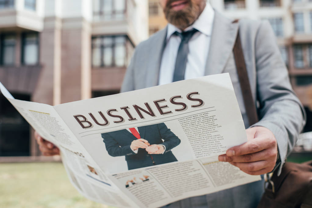 cropped view of businessman reading business newspaper in city - Photo, Image