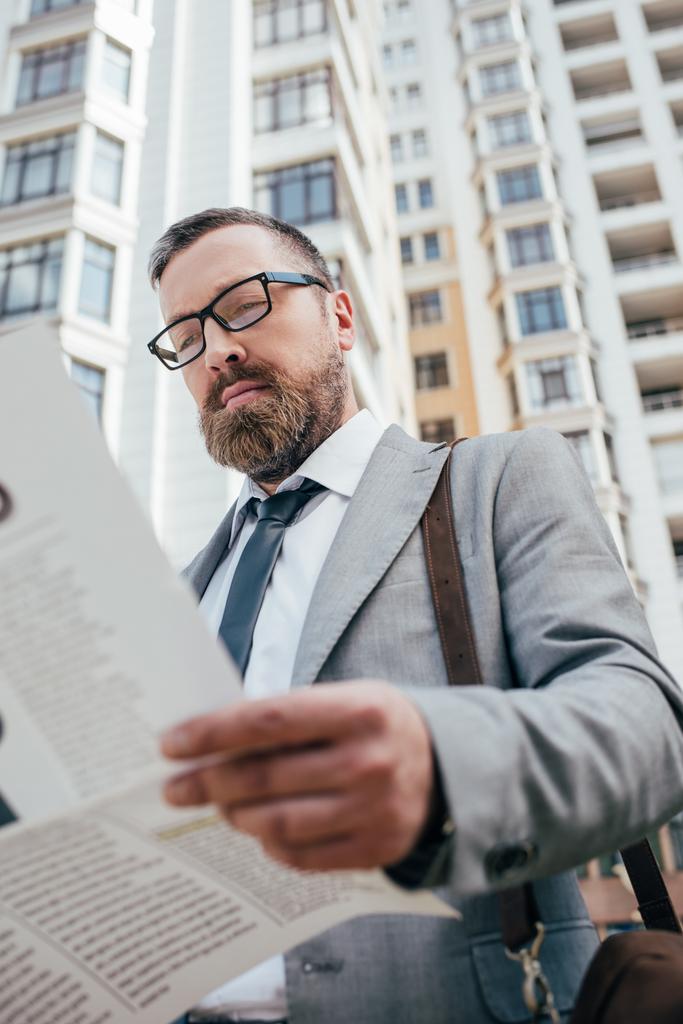 bebaarde zakenman lezen van de krant in de stad - Foto, afbeelding