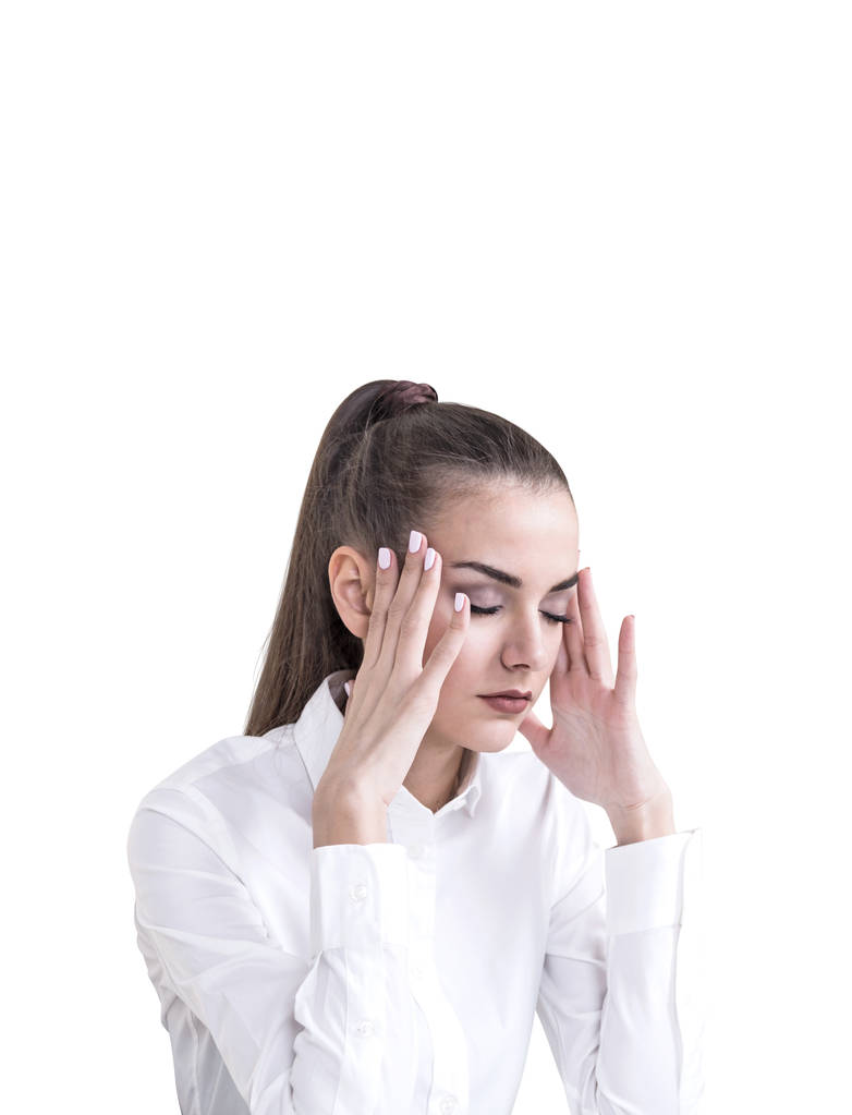 Напряженная молодая деловая женщина с длинными волосами в хвосте, в белой рубашке. У неё болит голова и она стоит с закрытыми глазами. Изолированный портрет
 - Фото, изображение