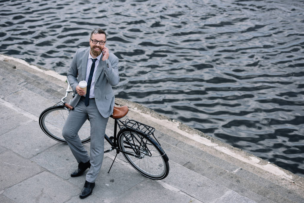 liikemies kahvia mennä puhumaan älypuhelimeen ja seisoo pyörä laiturilla
 - Valokuva, kuva
