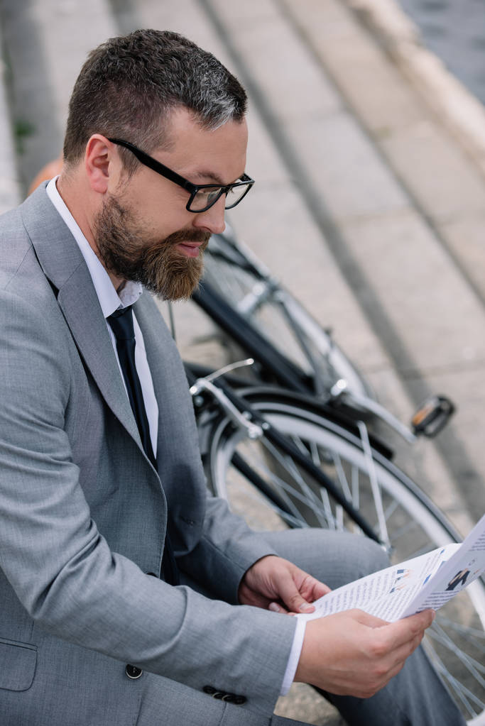 guapo barbudo hombre de negocios leyendo periódico en escaleras con bicicleta
 - Foto, imagen