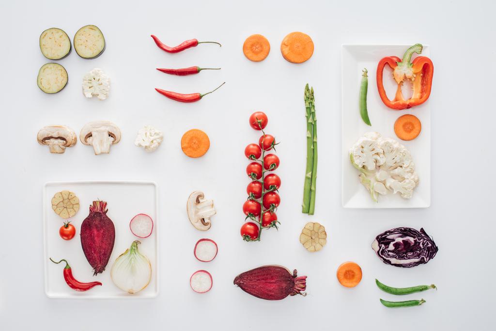 vista superior de platos blancos y verduras orgánicas frescas en rodajas aisladas en blanco
  - Foto, imagen