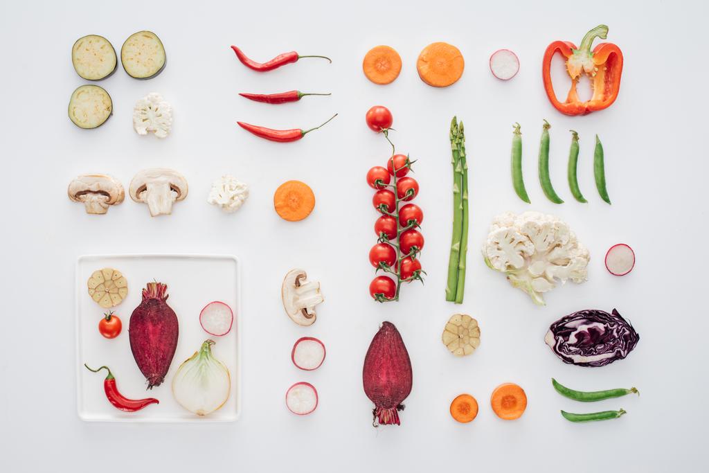 вид зверху на білу тарілку і свіжі нарізані органічні овочі ізольовані на білому
  - Фото, зображення