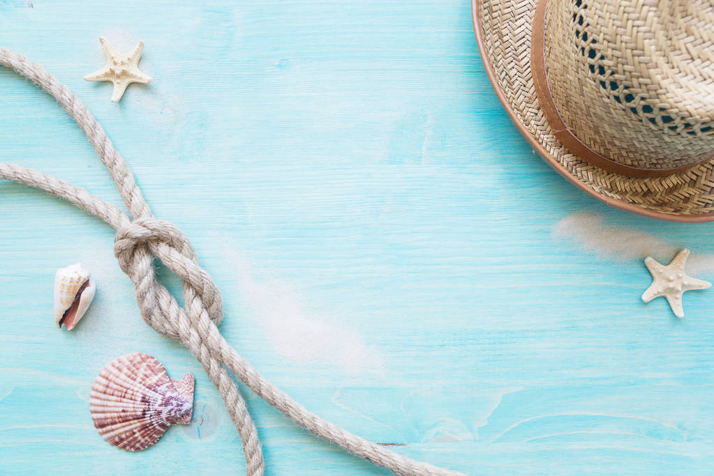Груба конопляна мотузка пов'язана вузловим морем, пеклами, морськими зірочками та солом'яним капелюхом на тлі блакитної зів'ялої дерев'яної палуби. Морська концепція
 - Фото, зображення