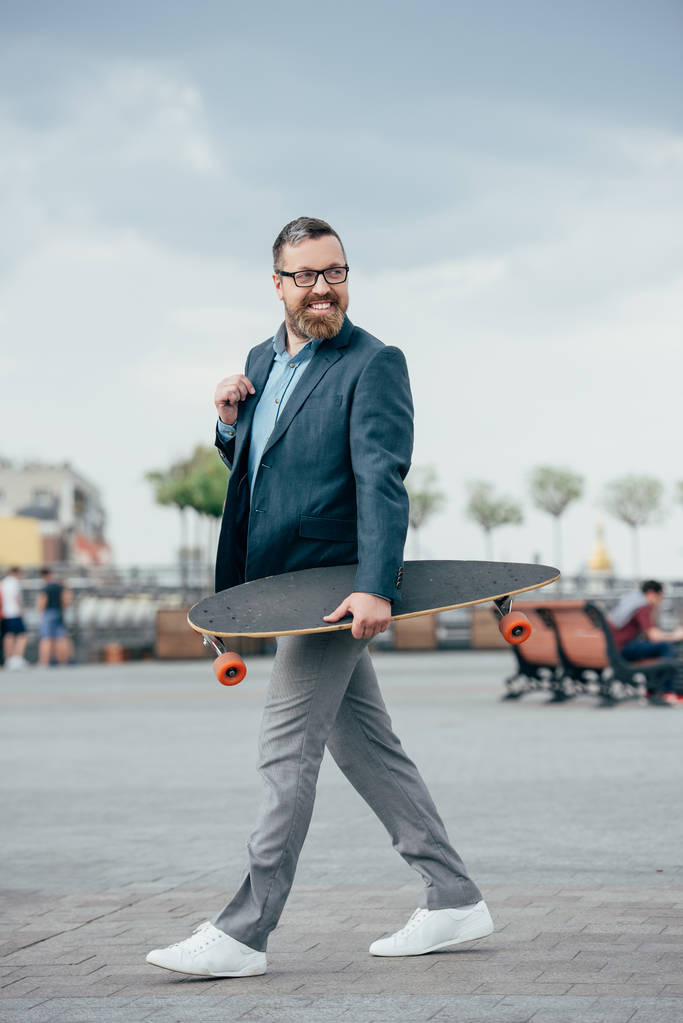 hombre barbudo guapo con longboard caminando en la ciudad
 - Foto, Imagen