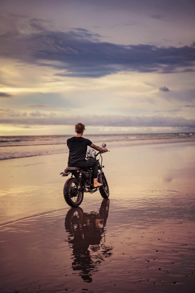 vue arrière du motard avec moto sur la plage de l'océan avec un temps nuageux
 - Photo, image