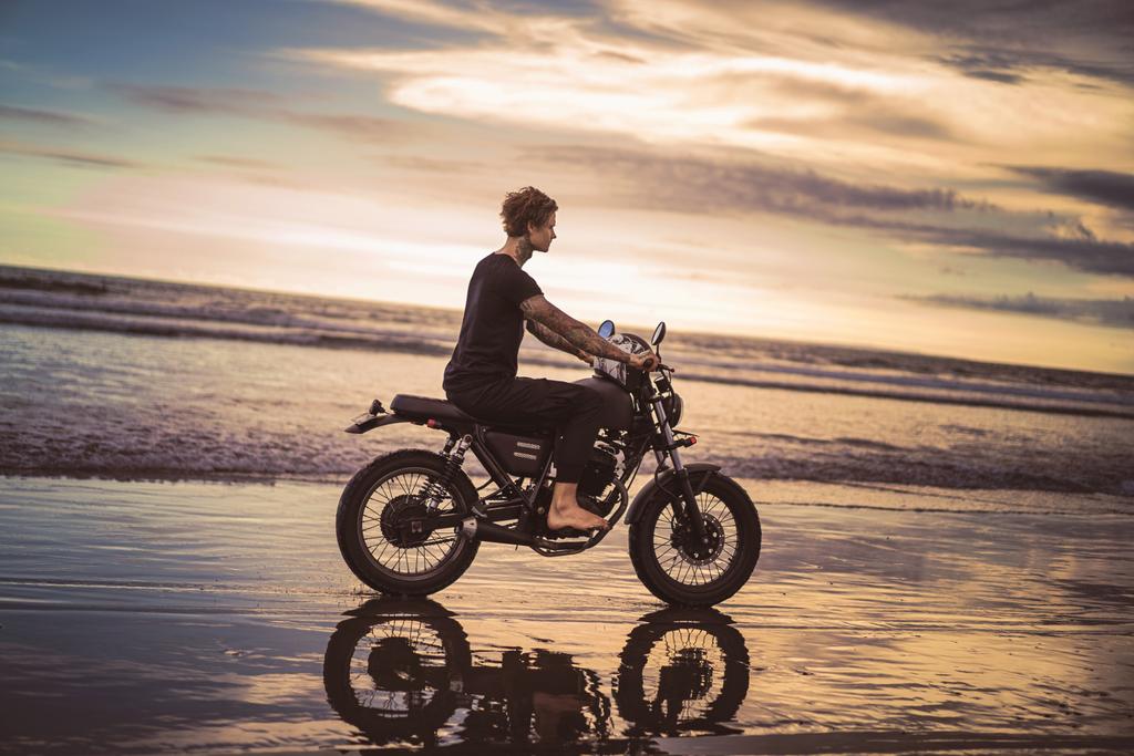 vue latérale de l'homme tatoué à moto sur la plage de l'océan pendant le beau lever du soleil
 - Photo, image