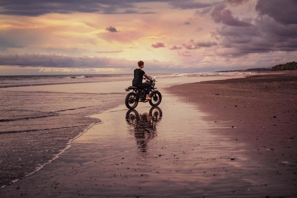 vue latérale de l'homme à moto sur le bord de la mer
 - Photo, image