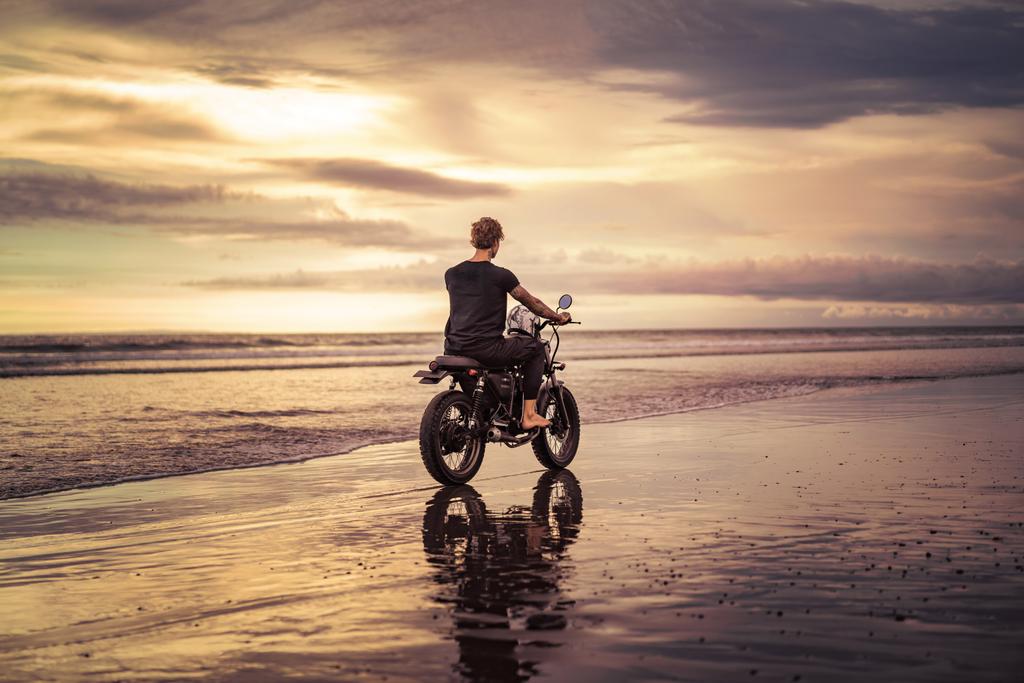 back view de motociclista tatuado andar de moto na praia do oceano
  - Foto, Imagem