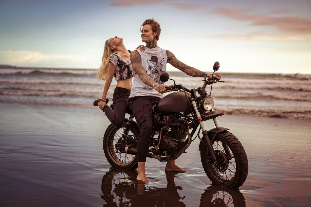 φίλη αγγίζοντας φίλο και να κάθεται σε μοτοσικλέτα στην ωκεάνια παραλία  - Φωτογραφία, εικόνα
