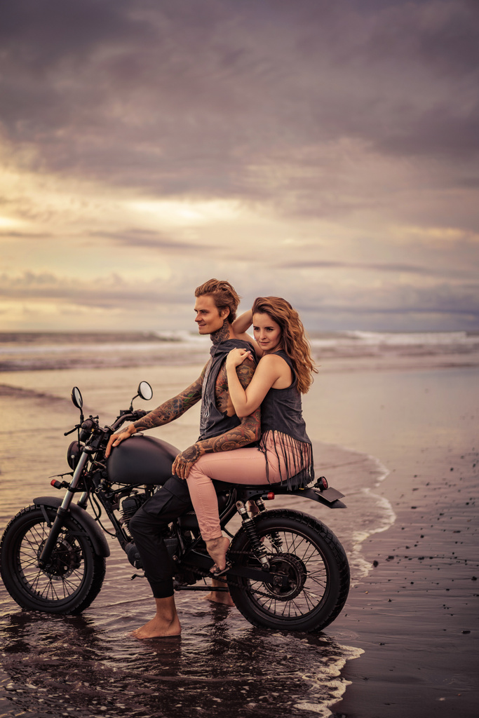çekici kız ve erkek arkadaşı gündoğumu sırasında motosiklet Plajı'nda oturan  - Fotoğraf, Görsel