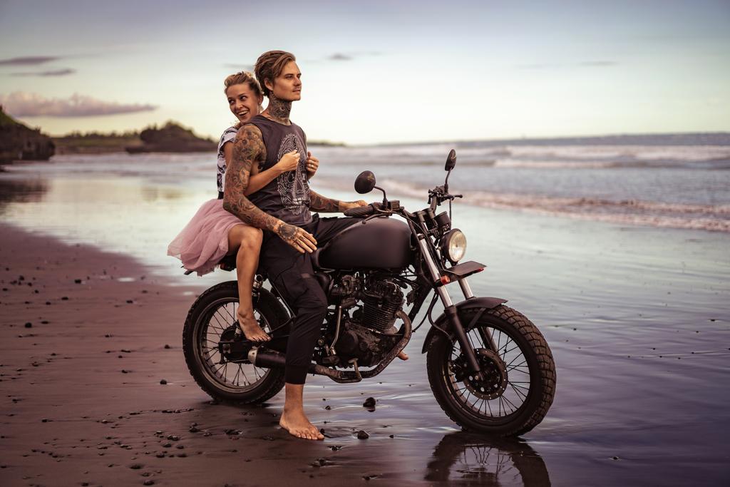 petite amie souriante étreignant petit ami sur la moto sur la plage de l'océan
 - Photo, image