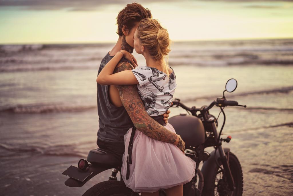 vášnivý pár objímání na motorce na pláži u oceánu během krásný východ slunce  - Fotografie, Obrázek