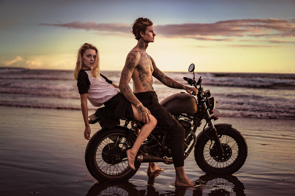 couple posing on motorcycle on ocean beach  - Photo, Image