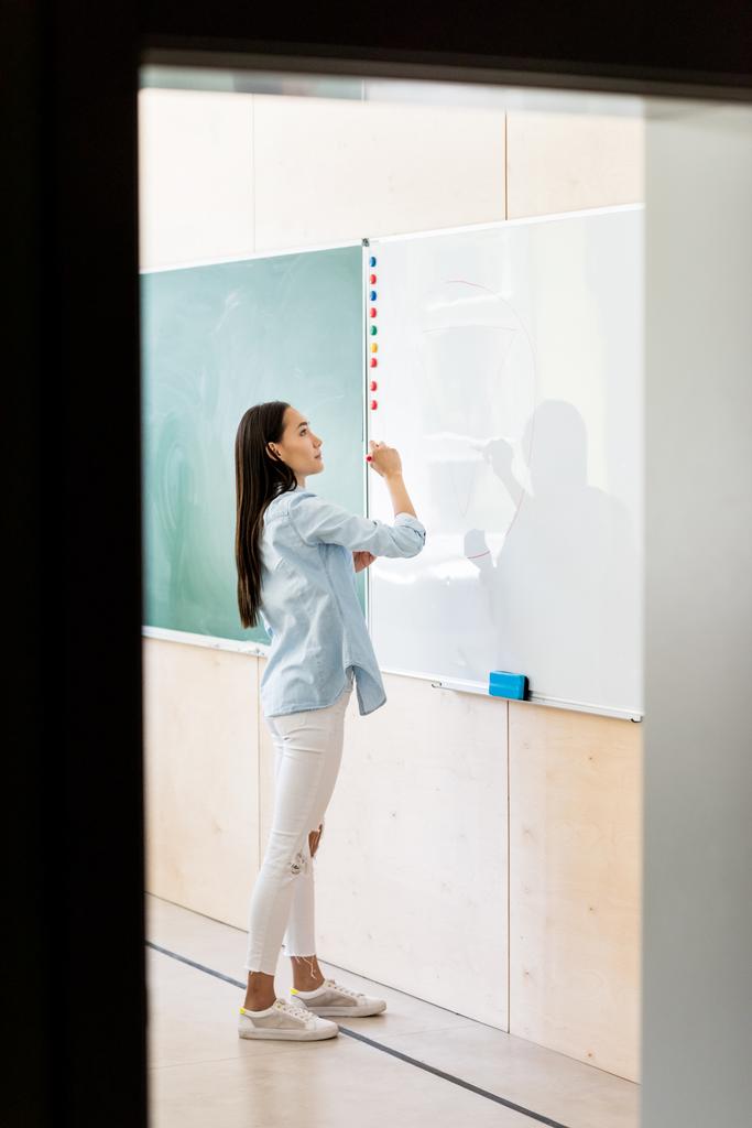 promyšlené Asijská studentka psaní na tabuli během lekce - Fotografie, Obrázek