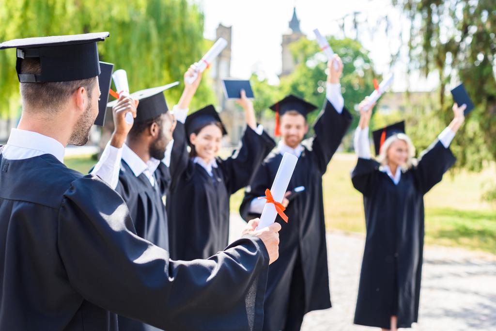νεαροί μαθητές ευτυχισμένη γιορτάζει την αποφοίτηση μαζί στο κολέγιο τετράγωνο - Φωτογραφία, εικόνα