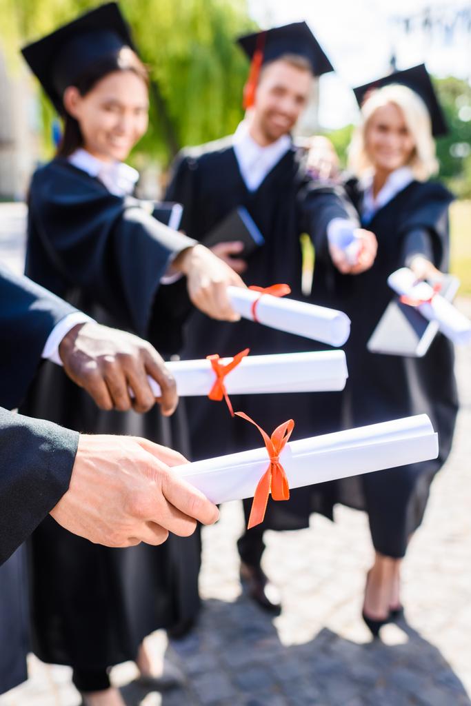 recortado tiro de jóvenes estudiantes graduados que poseen diplomas laminados
 - Foto, imagen
