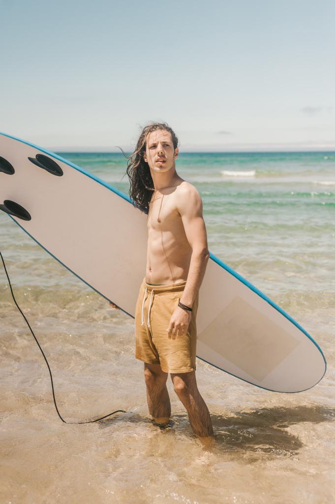 夏の日の海でサーフボードに立って若い男 - 写真・画像