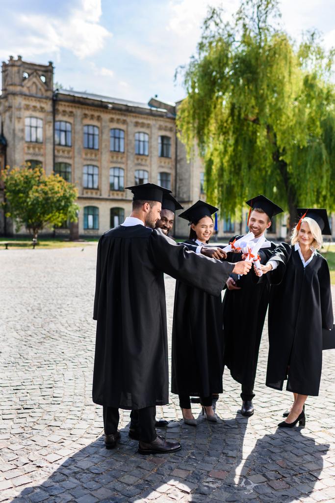 junge glückliche Absolventen machen Team-Geste mit gerollten Diplomen - Foto, Bild