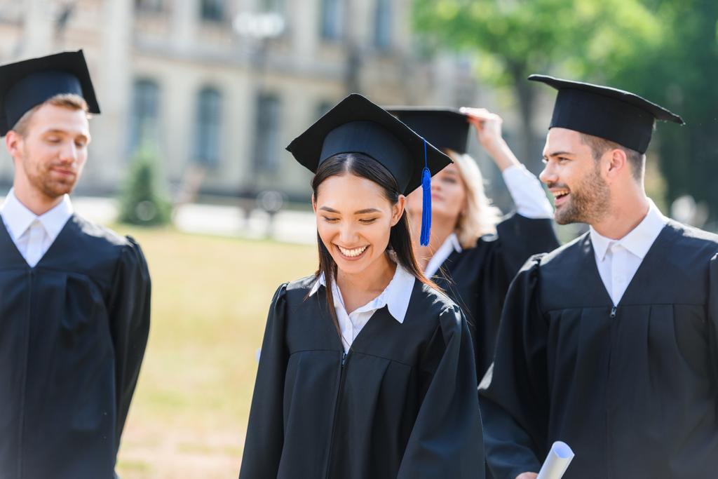 souriant jeunes diplômés étudiants en capes sur le jardin universitaire
 - Photo, image