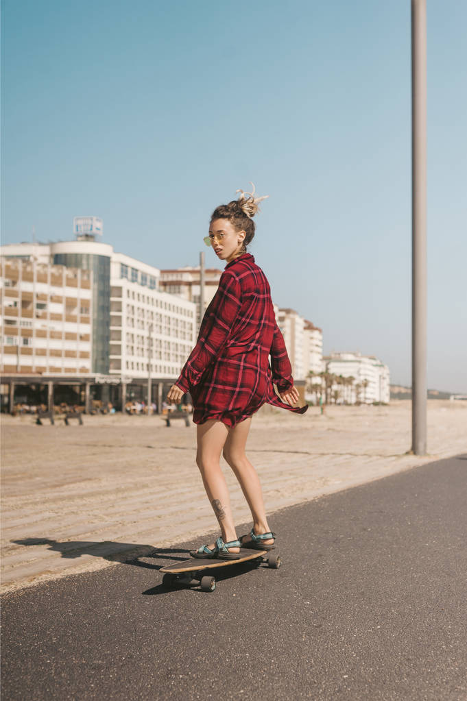 giovane donna in occhiali da sole e pattinaggio camicia sul longboard in strada in Portogallo
 - Foto, immagini