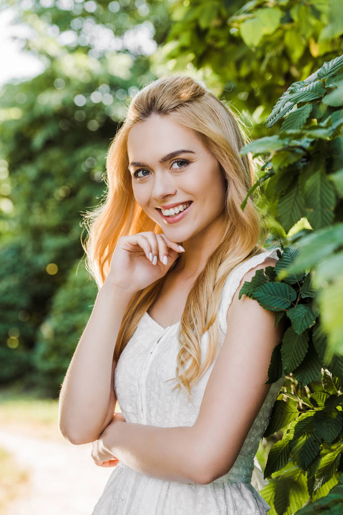 красива молода блондинка в білій сукні посміхається на камеру
 - Фото, зображення