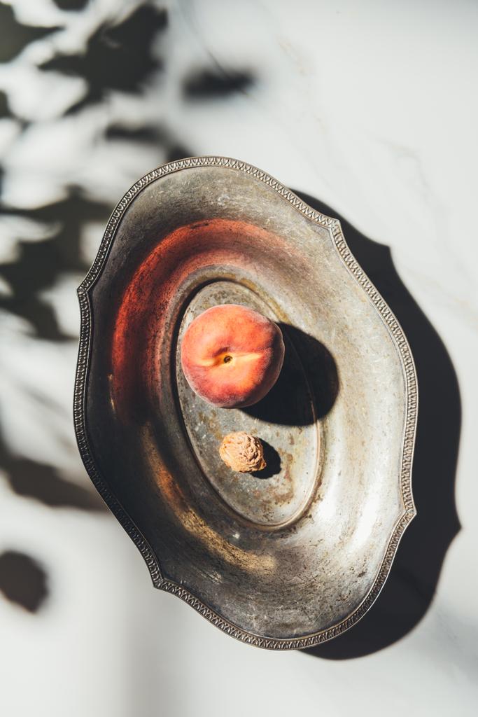 сверху вид персика и персика в металлической чаше на светлом мраморном столе с тенями
 - Фото, изображение