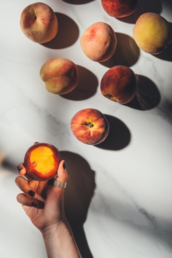 osittainen näkymä naisen käsi ja kypsiä persikoita kevyt marmori pöytälevy varjoilla
 - Valokuva, kuva