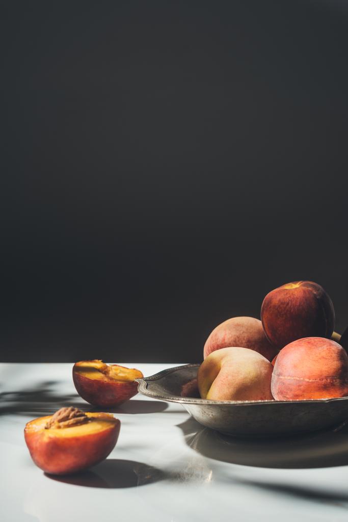 food composition with ripe peaches in metal bowl on black backdrop - Photo, Image