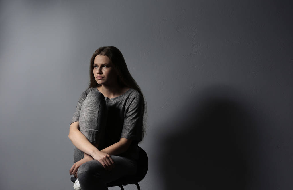 Депресивна молода жінка на сірому фоні
 - Фото, зображення