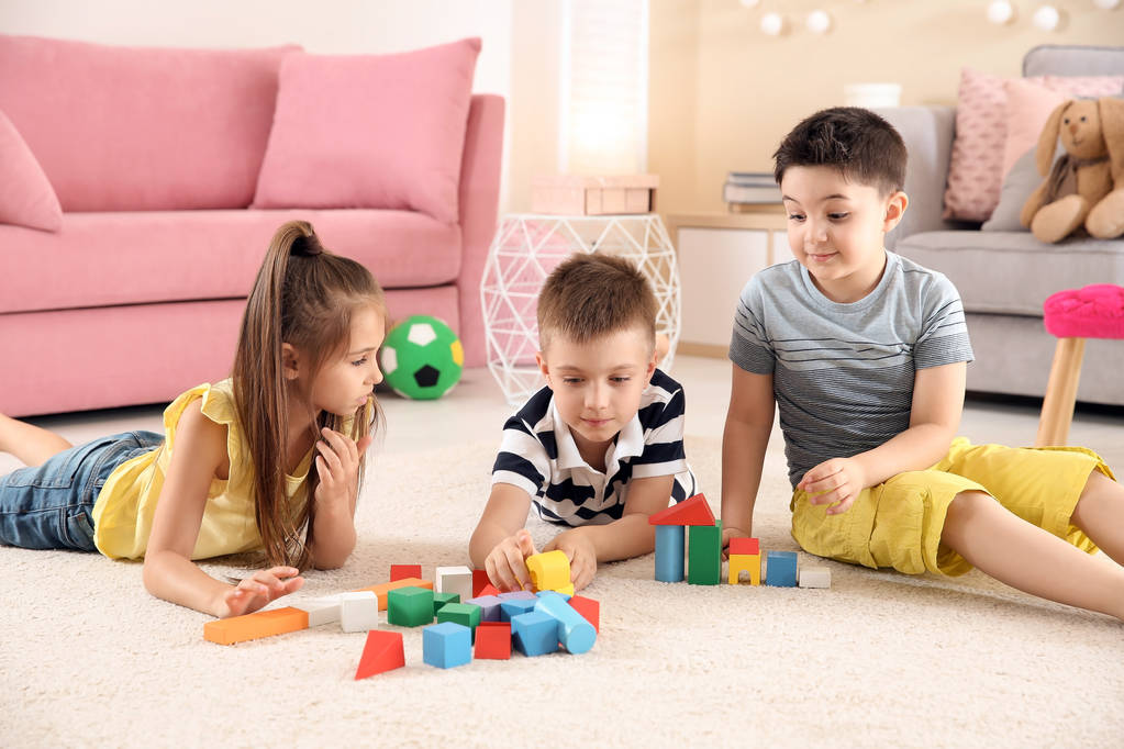 Милі маленькі діти граються з будівельними блоками на підлозі, в приміщенні
 - Фото, зображення