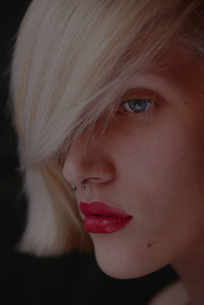 Portret van mooie blonde vrouw met een piercing in de neus en rode lippen  - Foto, afbeelding