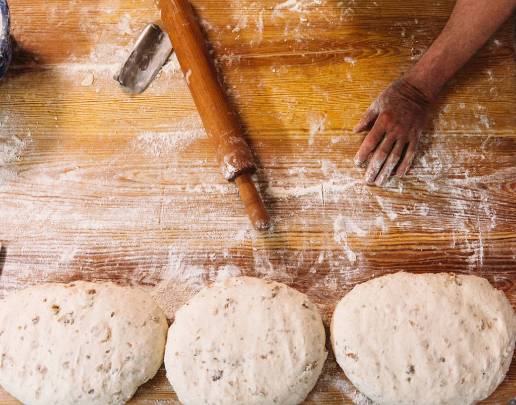 Il fornaio maschile prepara il pane. Panettiere impastare l'impasto con farina. A fare il pane. Vista dall'alto. Stile rustico e tradizionale
. - Foto, immagini