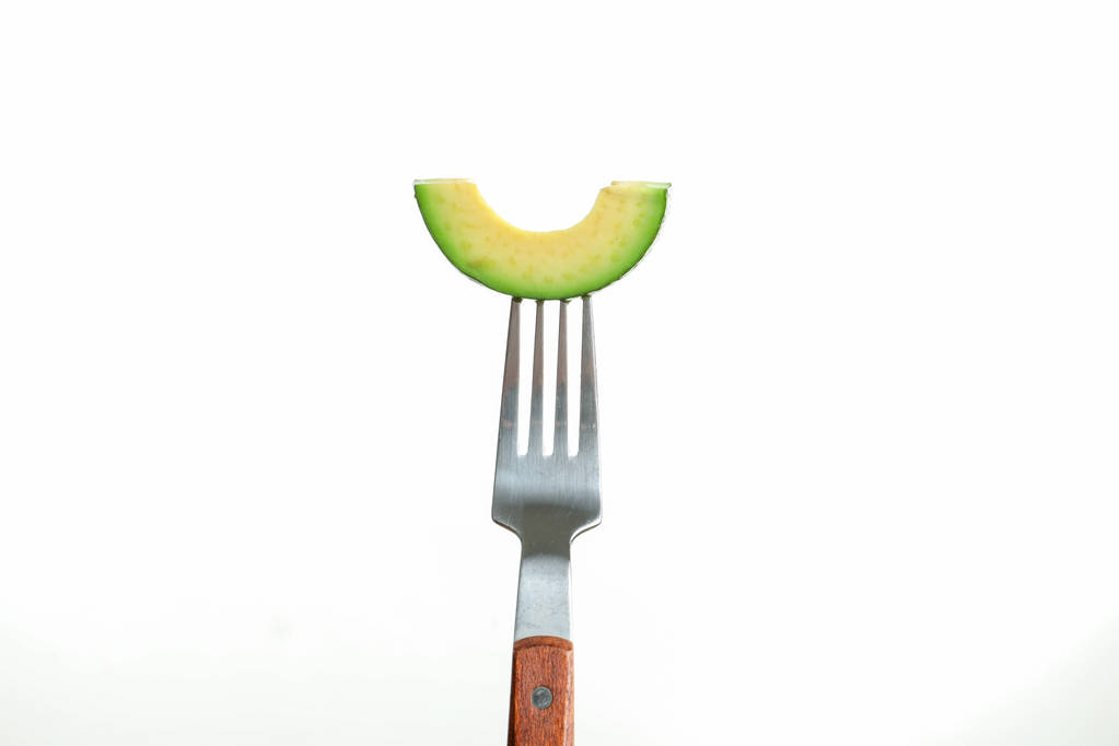 Вилка зі скибочкою авокадо на білому тлі
 - Фото, зображення