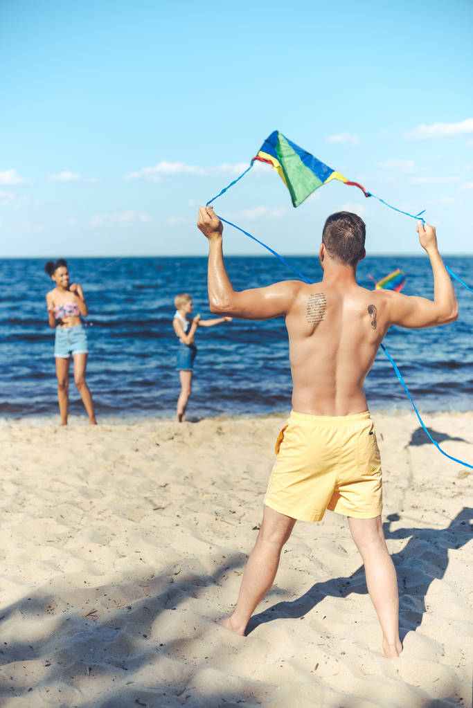 вибірковий фокус мультикультурних друзів з повітряним змієм, що проводить час на піщаному пляжі разом
 - Фото, зображення