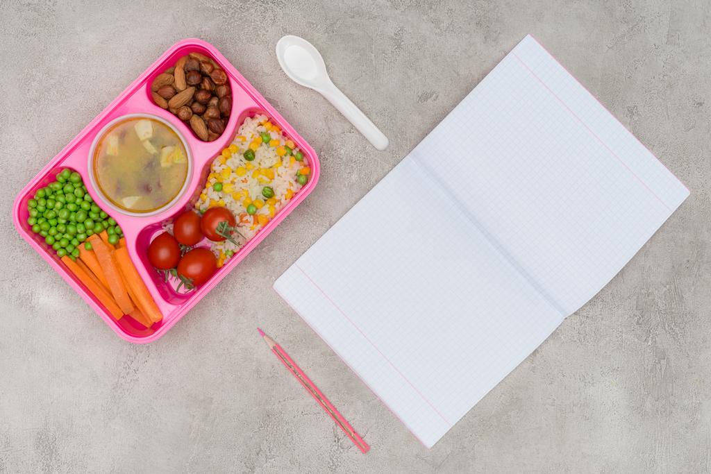 вид на поднос с детским обедом для школы и открытая тетрадь на мраморном столе
 - Фото, изображение