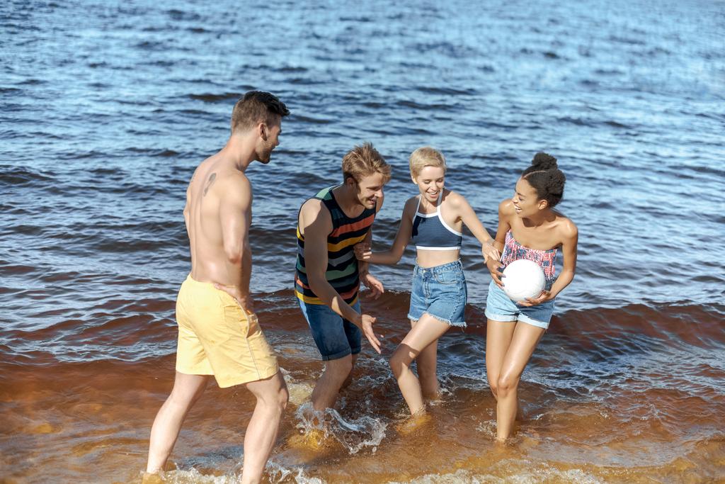 szczęśliwy międzyrasowy grupowy przyjaciół się z siatkówka piłka zabawy nad morzem - Zdjęcie, obraz