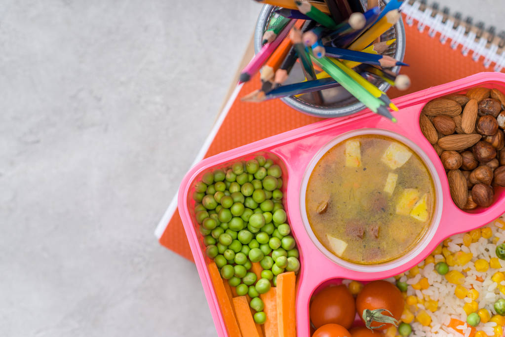 вид на поднос с детским обедом для школы и цветные карандаши на столе
 - Фото, изображение