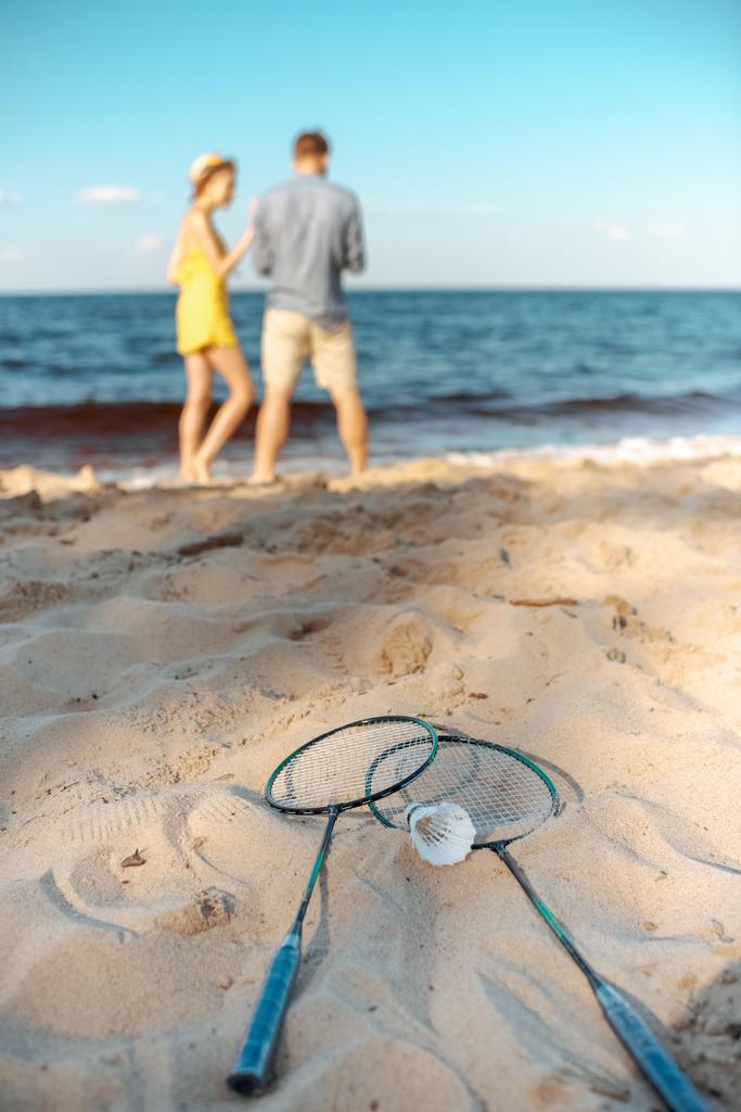 selective focus of badminton equipment and couple on sandy beach - Photo, Image