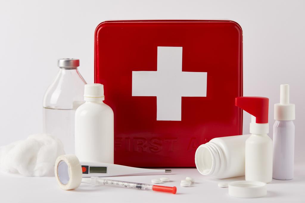 κοντά shot της κόκκινο πρώτες βοήθειες kit box με διάφορες ιατρικές φιάλες και προμήθειες σε λευκό - Φωτογραφία, εικόνα